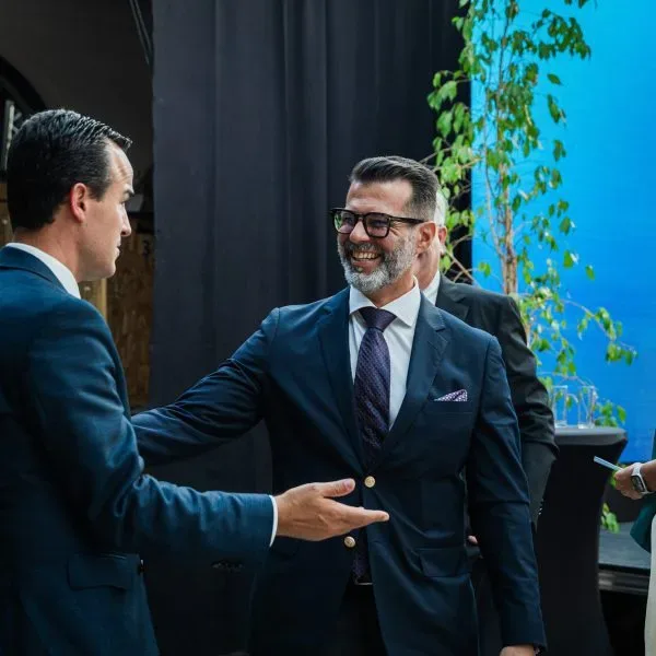 Participantes a conversar e a sorrir num evento do heróisP, com um ecrã azul ao fundo